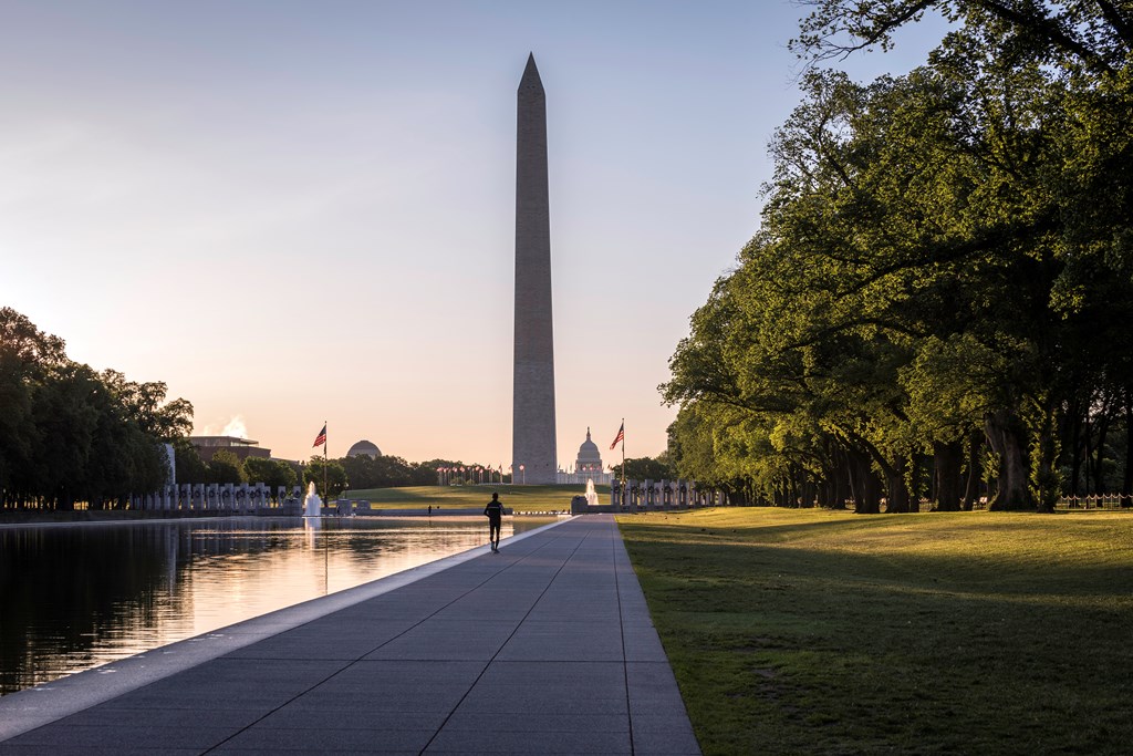 Jogger at The Reflecting Pool in Washington DC with the Washington Monument in the Background.