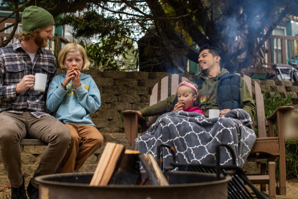 Two men and two kids around a campfire at anta Cruz Monterey KOA